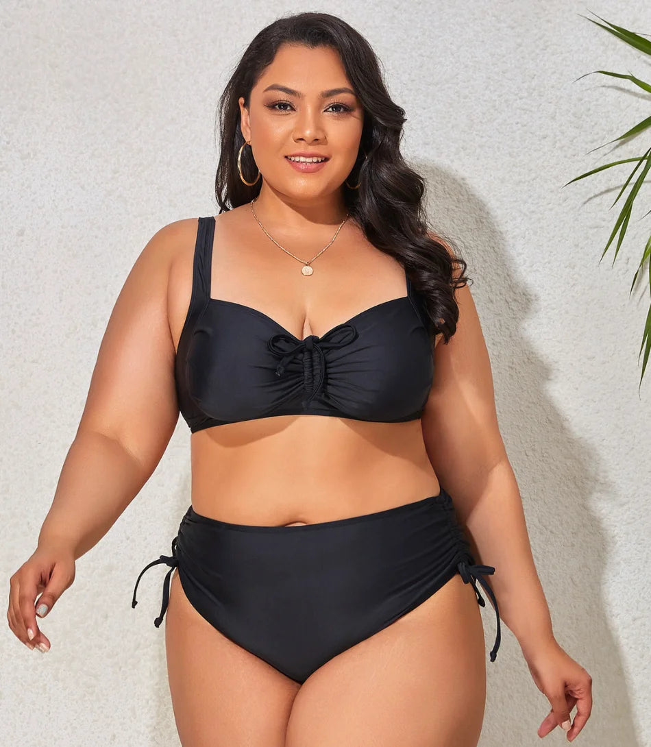 Mulher vestindo um biquíni plus size cintura alta com ajuste lateral, tecido preto resistente e alças largas ajustáveis, ideal para momentos na praia.