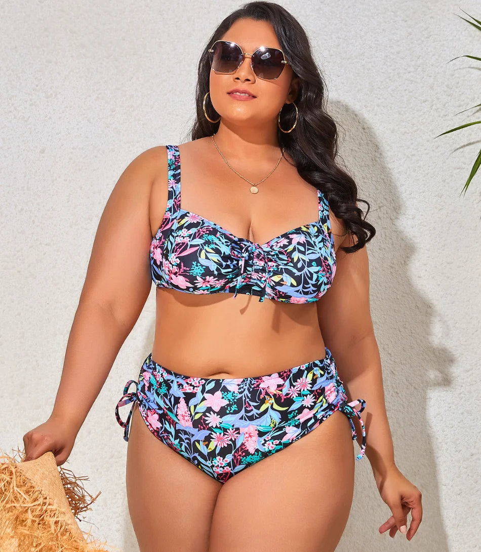 Mulher vestindo um biquíni plus size cintura alta com ajuste lateral, tecido preto resistente e alças largas ajustáveis, ideal para momentos na praia.