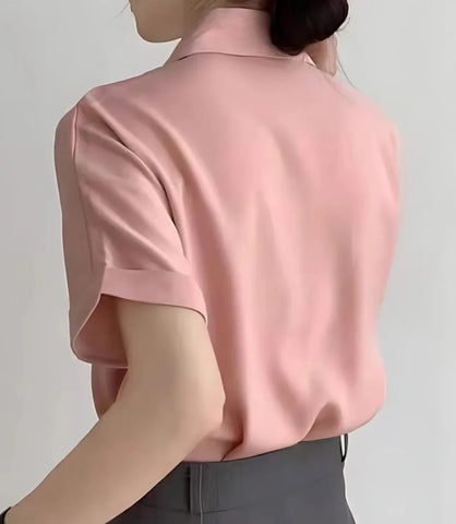 Blusa feminina em cetim com botões, gola dobrada e mangas curtas dobradas, ideal para composições elegantes e casuais, com caimento sofisticado.