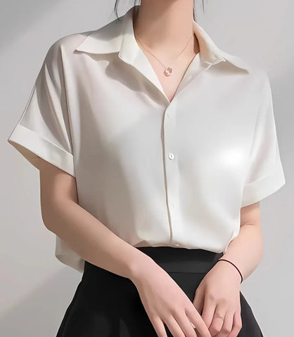 Blusa feminina em cetim com botões, gola dobrada e mangas curtas dobradas, ideal para composições elegantes e casuais, com caimento sofisticado.