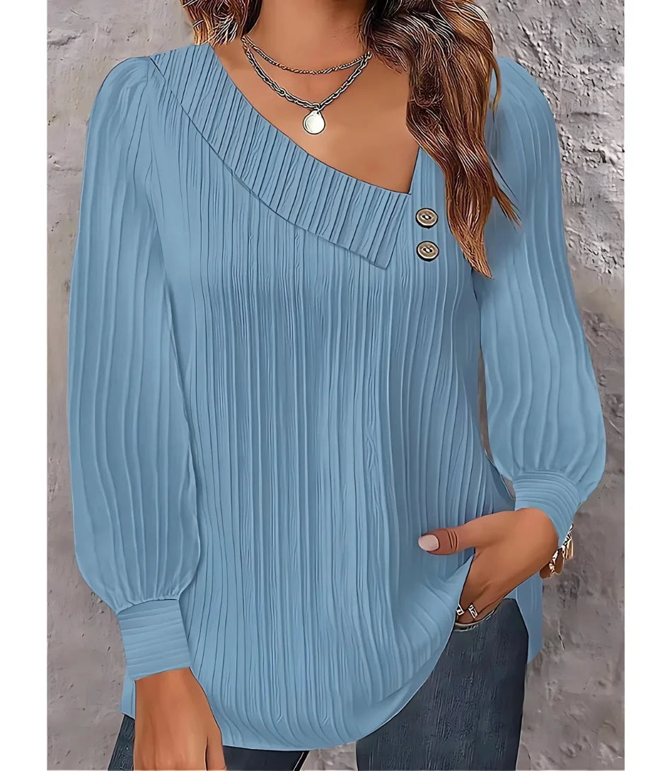 Blusa feminina plissada com botões no ombro, design elegante, mangas bufantes e decote assimétrico, ideal para looks sofisticados.