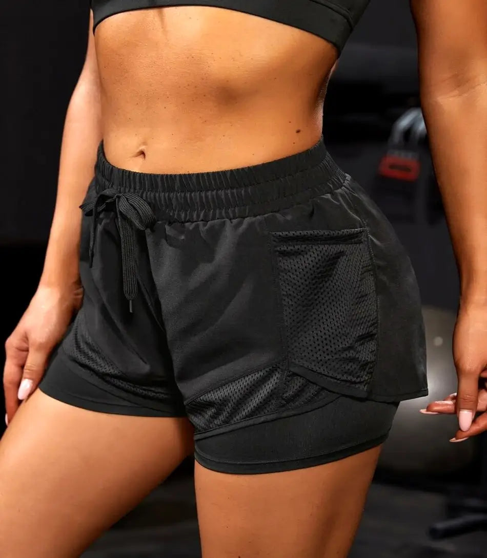 Shorts Fitness Feminino preto com bolsos invisíveis, cintura alta e tecido de secagem rápida, ideal para treinos e conforto diário. preto