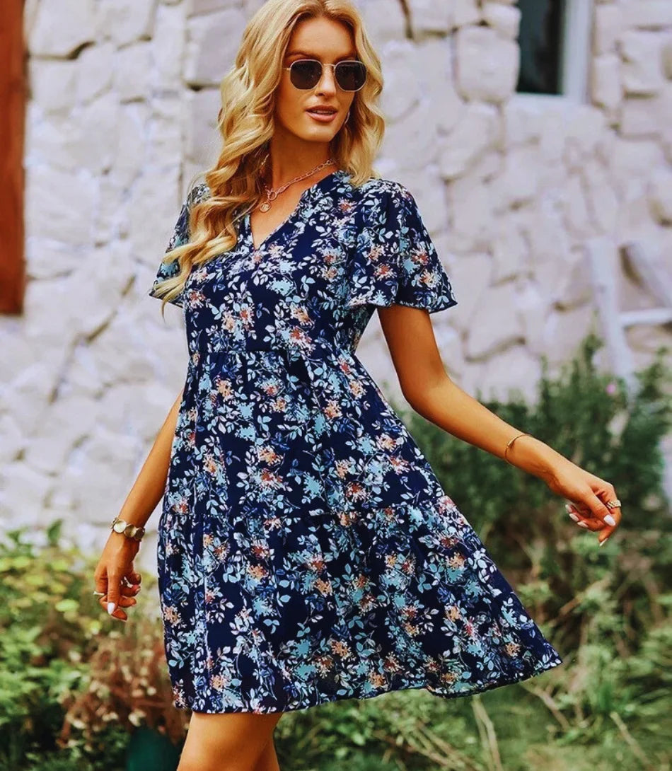 Vestido Boho Estampado Curto com decote em V, mangas curtas e estampa floral, ideal para looks boho chic elegantes e confortáveis.