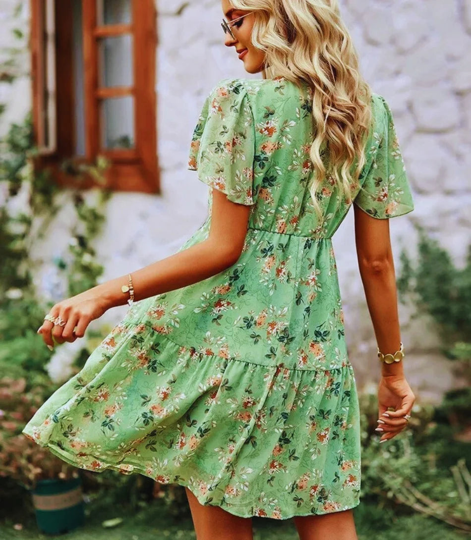 Vestido Boho Estampado Curto com decote em V, mangas curtas e estampa floral, ideal para looks boho chic elegantes e confortáveis.