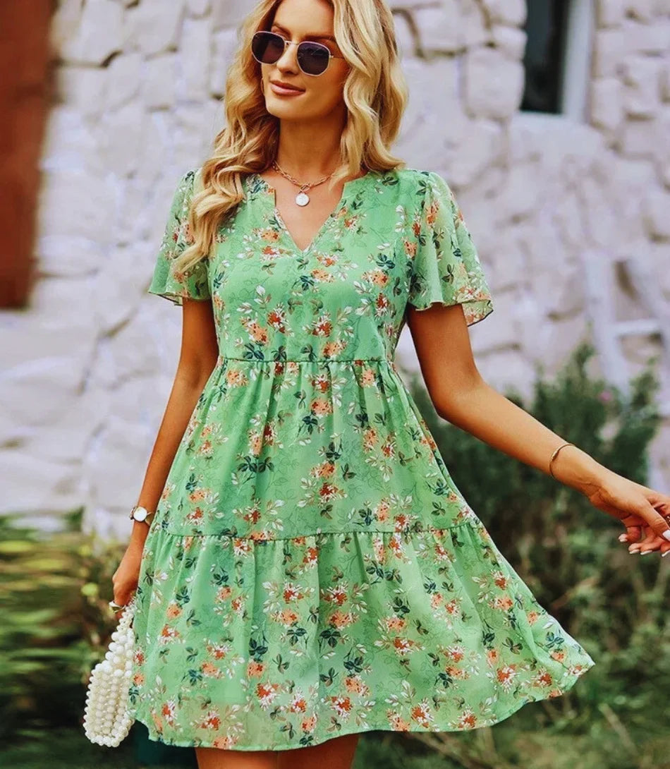 Vestido Boho Estampado Curto com decote em V, mangas curtas e estampa floral, ideal para looks boho chic elegantes e confortáveis.