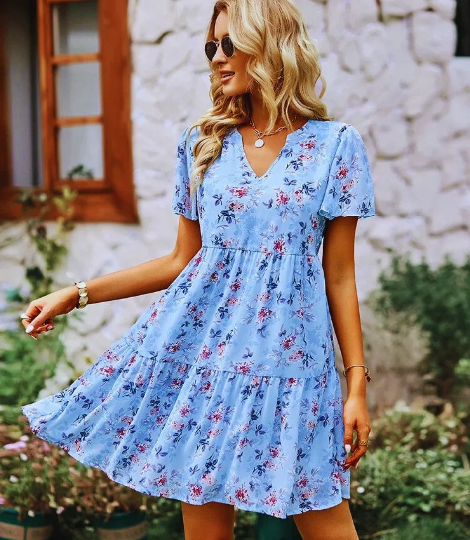 Vestido Boho Estampado Curto com decote em V, mangas curtas e estampa floral, ideal para looks boho chic elegantes e confortáveis.