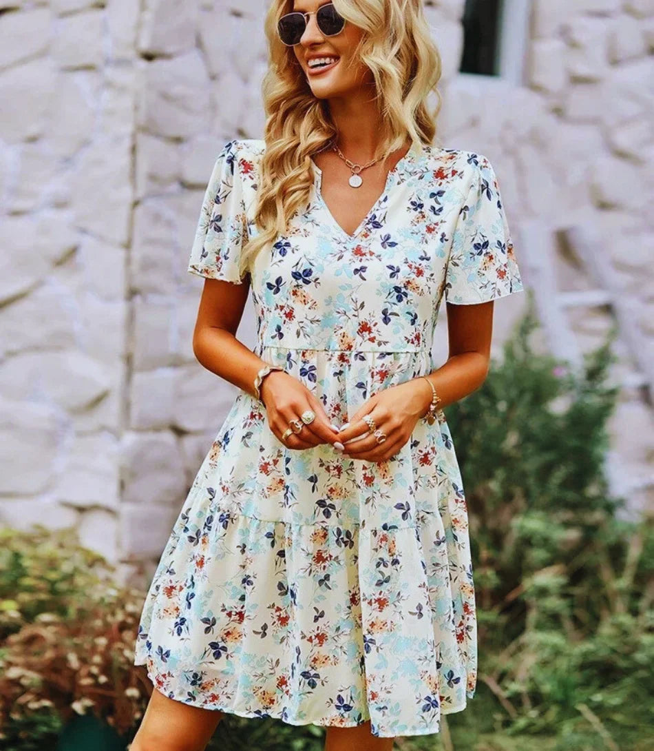 Vestido Boho Estampado Curto com decote em V, mangas curtas e estampa floral, ideal para looks boho chic elegantes e confortáveis.