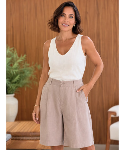 Modelo usando bermuda alfaiataria feminina de linho na cor bege nude com regata branca