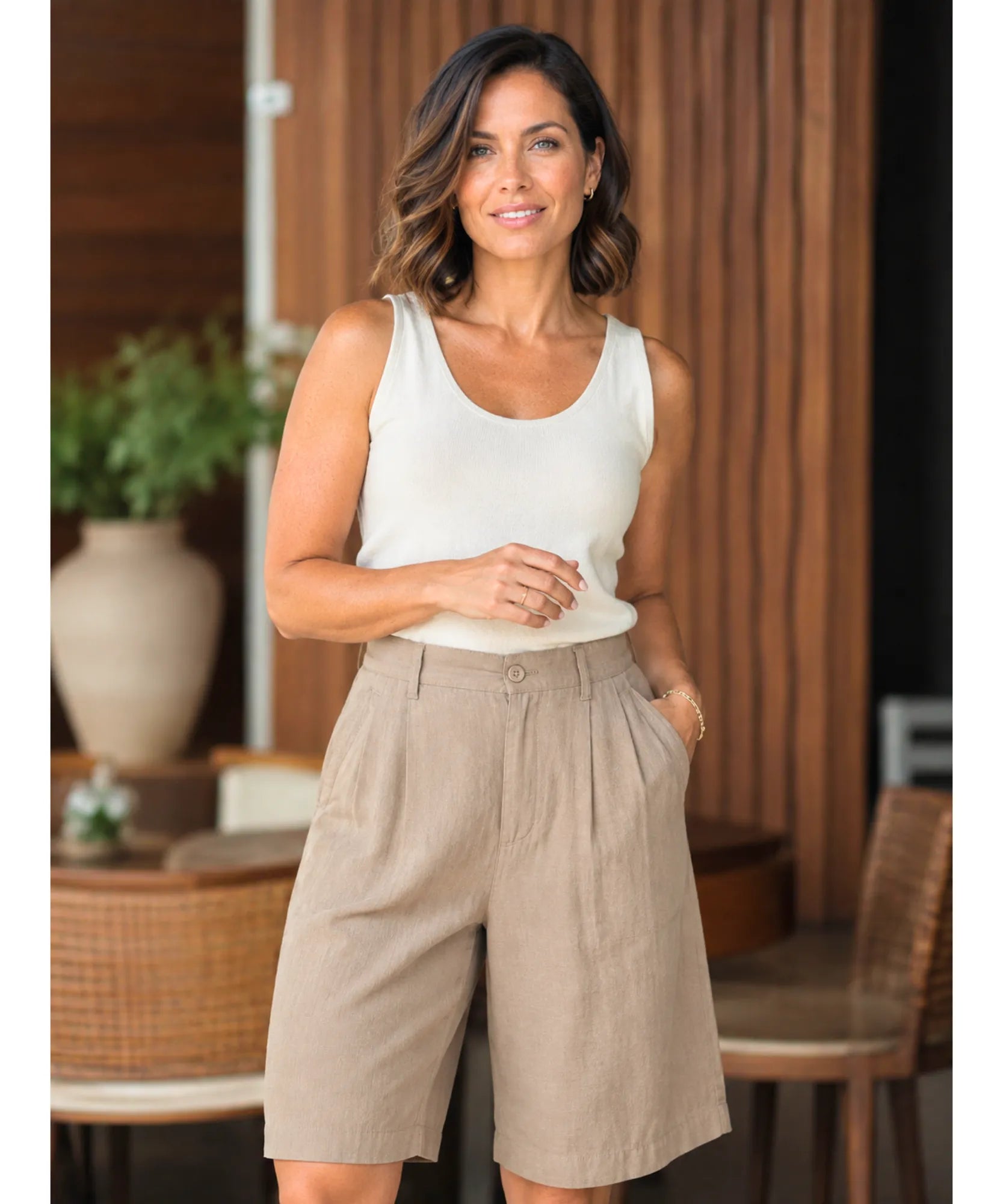 Modelo usando bermuda feminina de linho na cor nude bege com regata branca, look de verao