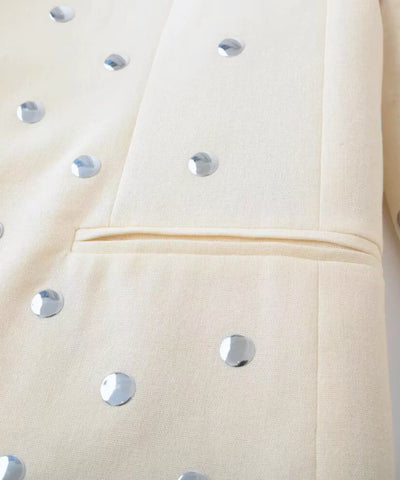 Detalhe das tachas metalizadas no bolso e na manga do blazer bege feminino