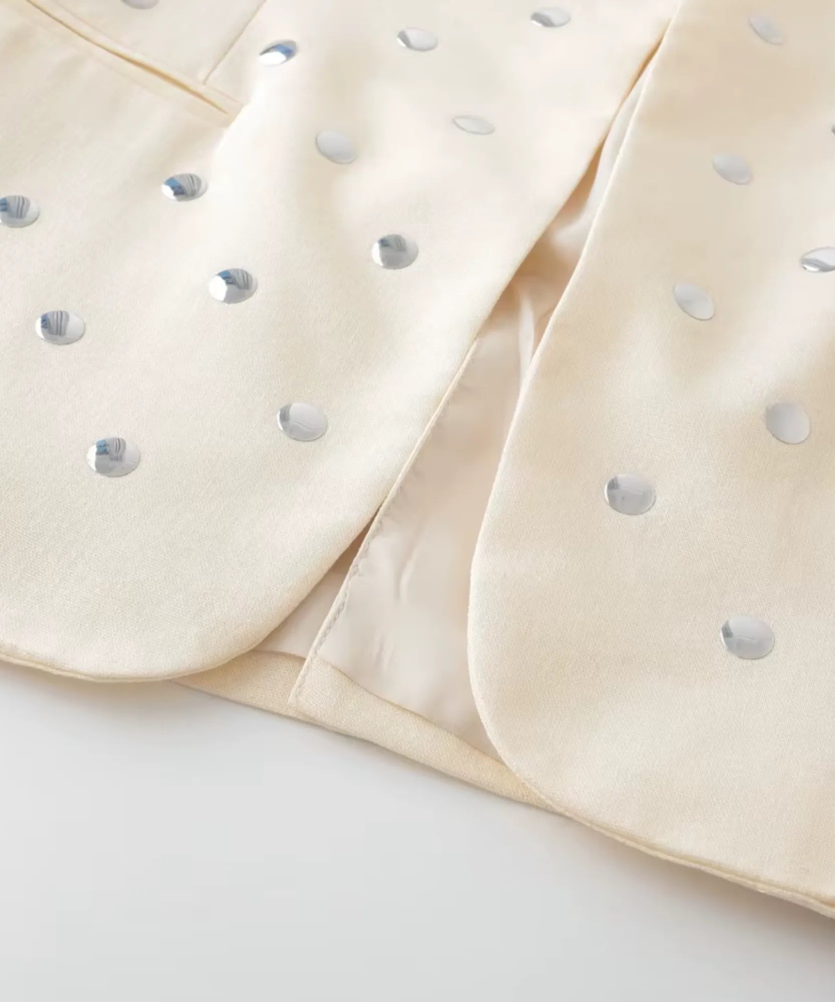 Detalhe das tachas metalizadas na gola do blazer bege feminino