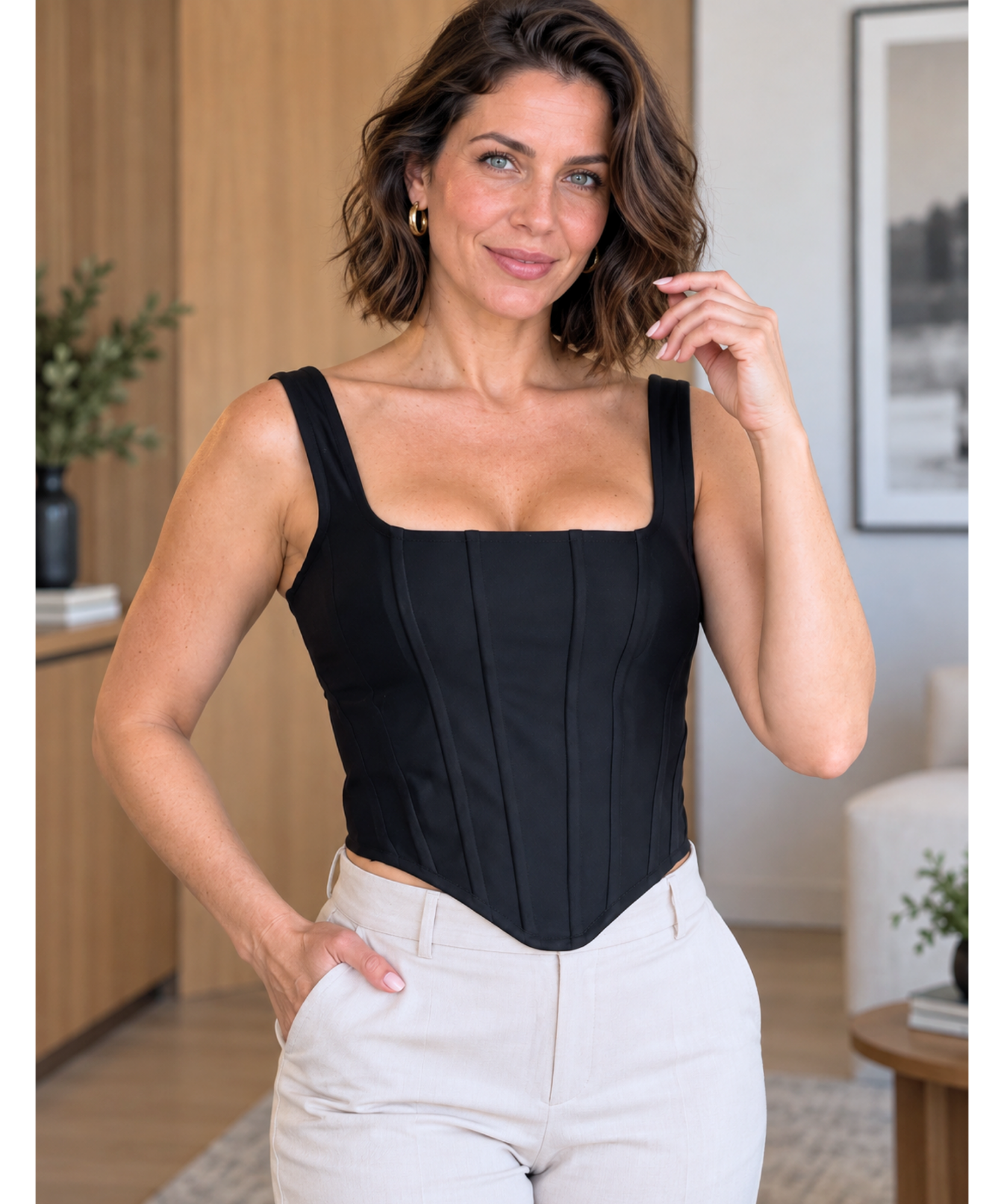 Blusa corset preta de malha com a mão na cintura mostrando o efeito modelador