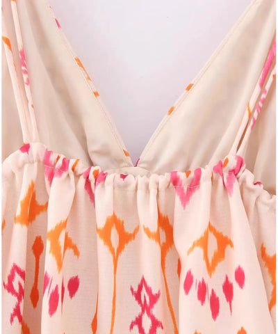 Detalhe das alças finas reguláveis e do decote da blusa cropped boho bege com estampa rosa e laranja