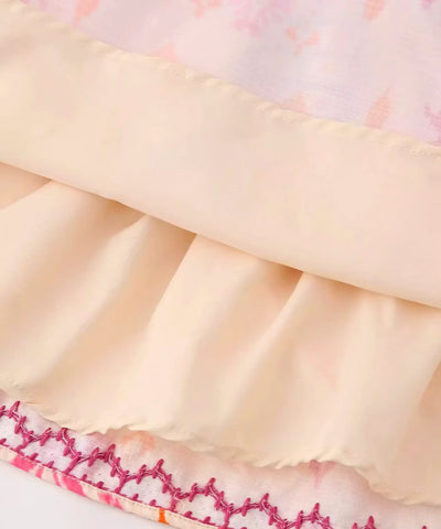 Detalhe da barra da blusa cropped boho bege com bordado em crochê rosa e vermelho