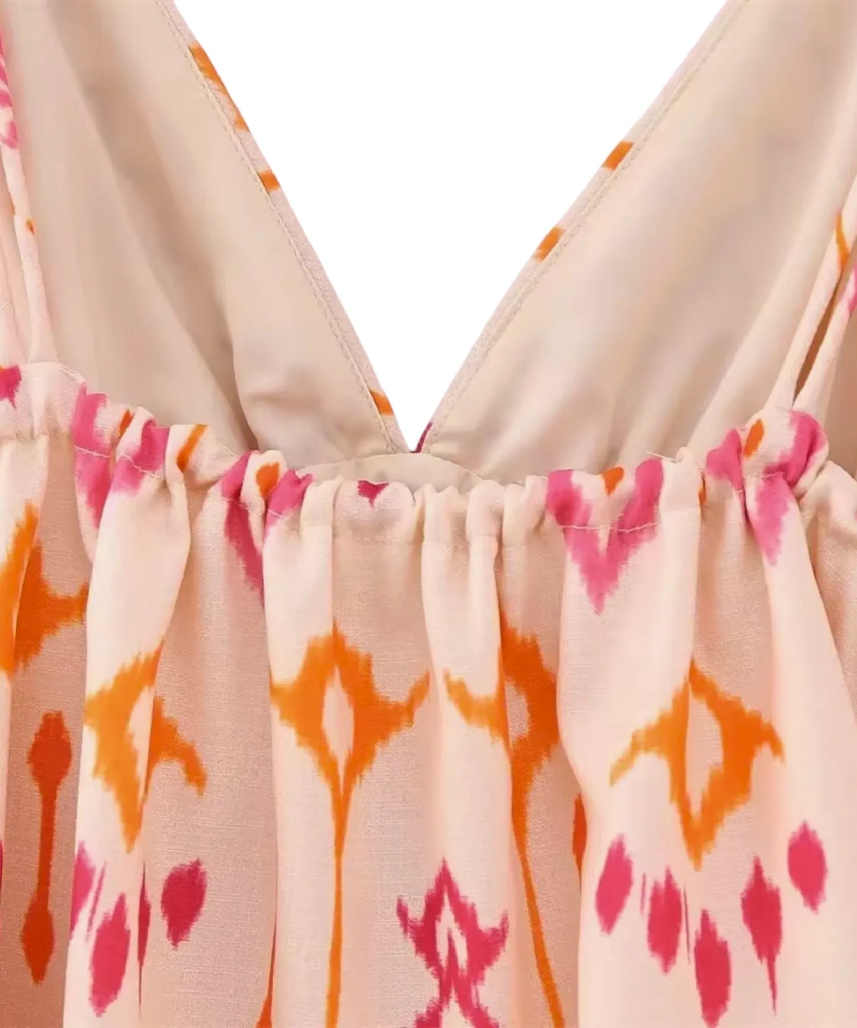 Detalhe do decote V da blusa cropped boho com bordado crochê rosa sobre tecido bege e estampa laranja