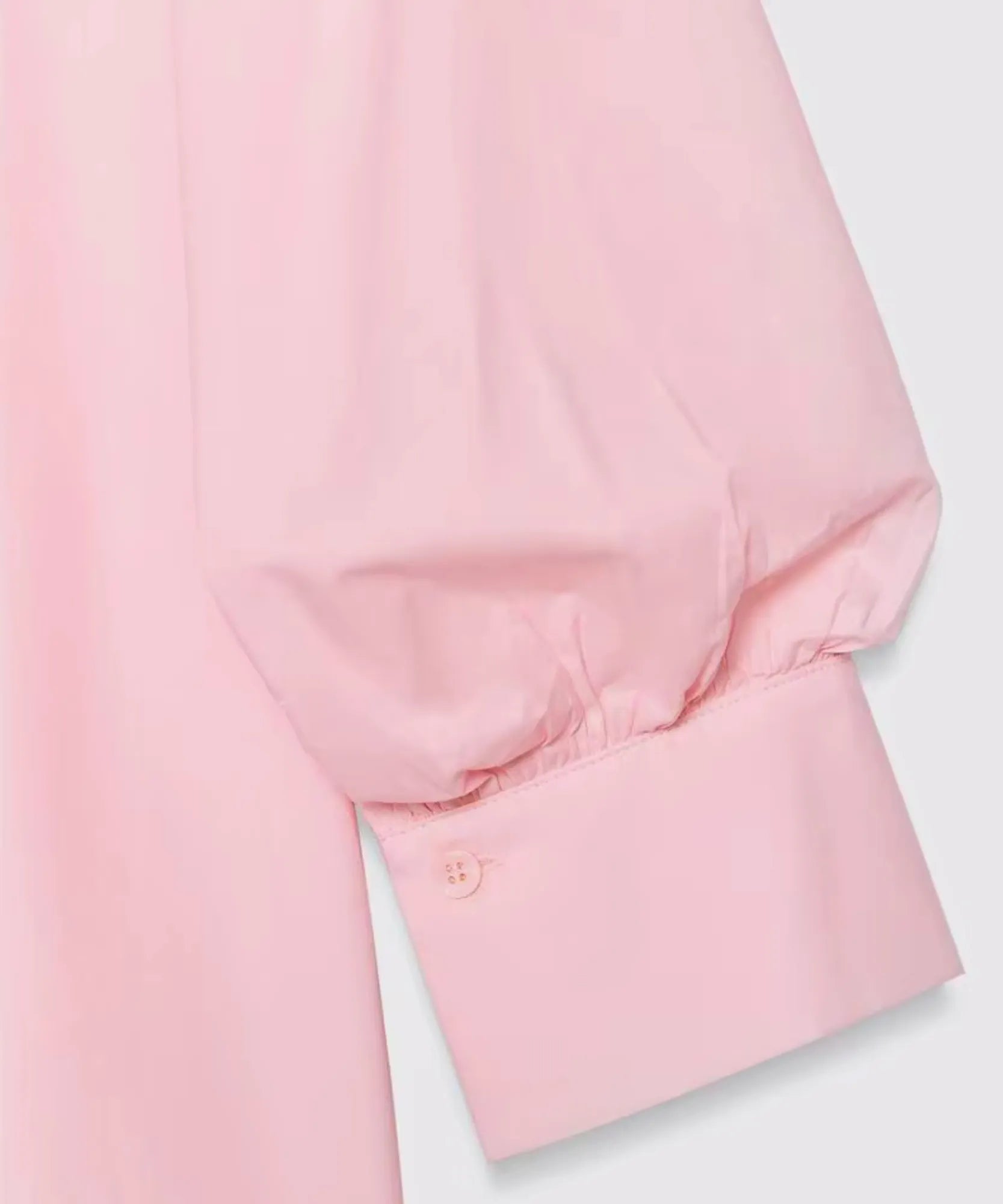 Detalhe do punho abotoado da manga bufante rosa