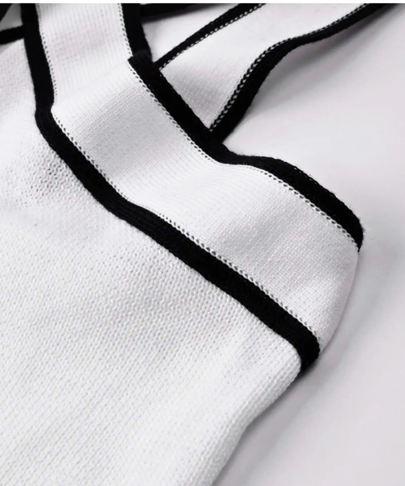 Acabamento em viés preto na borda da blusa regata feminina branca de malha lisa