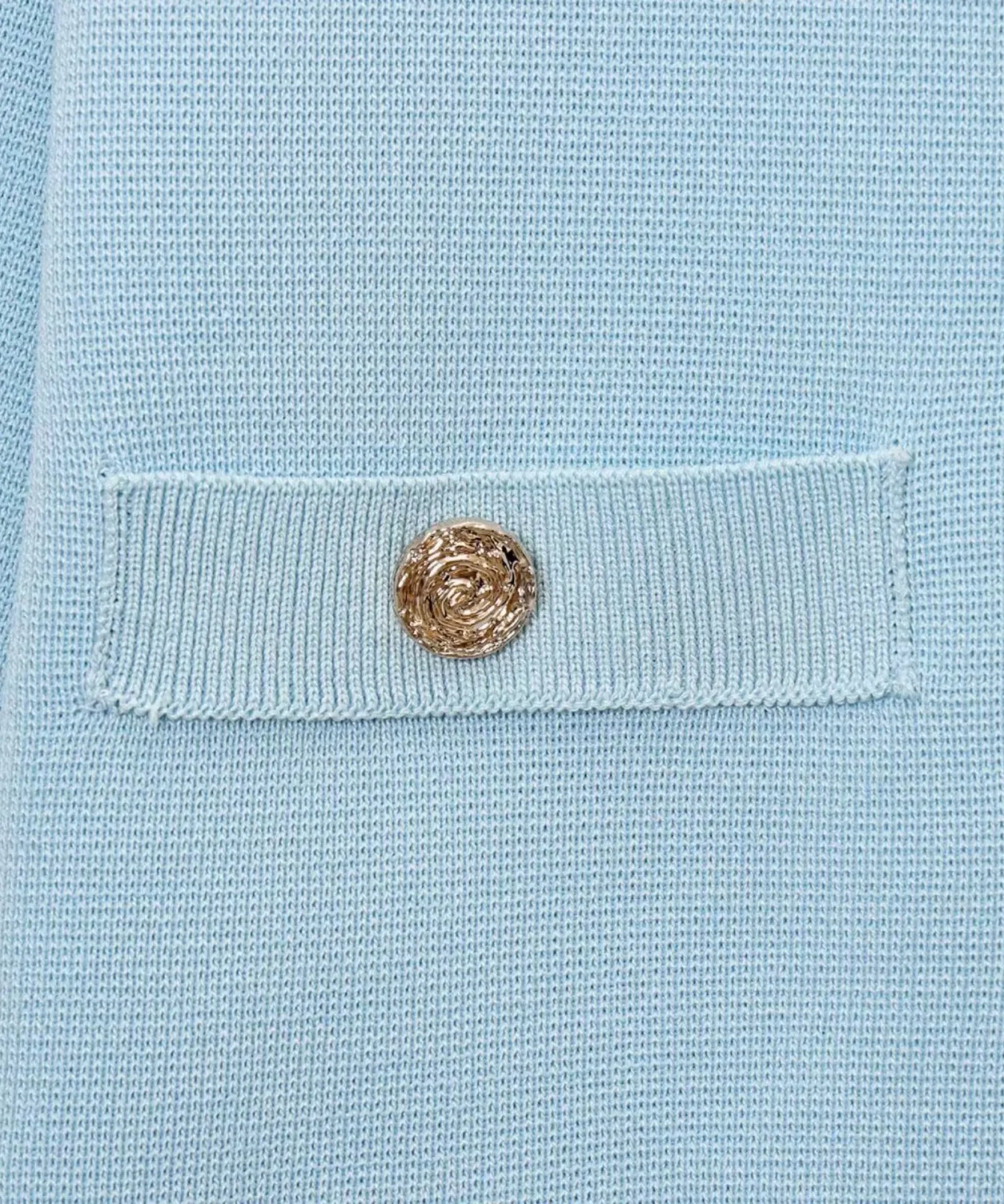 Detalhe do bolsinho com botão dourado da blusa tricot manga curta azul claro