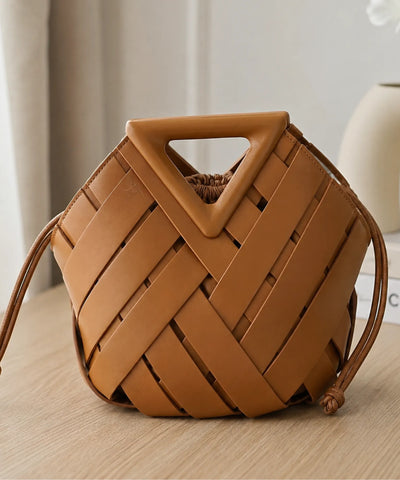 Bolsa feminina trançada caramelo still sobre mesa de madeira