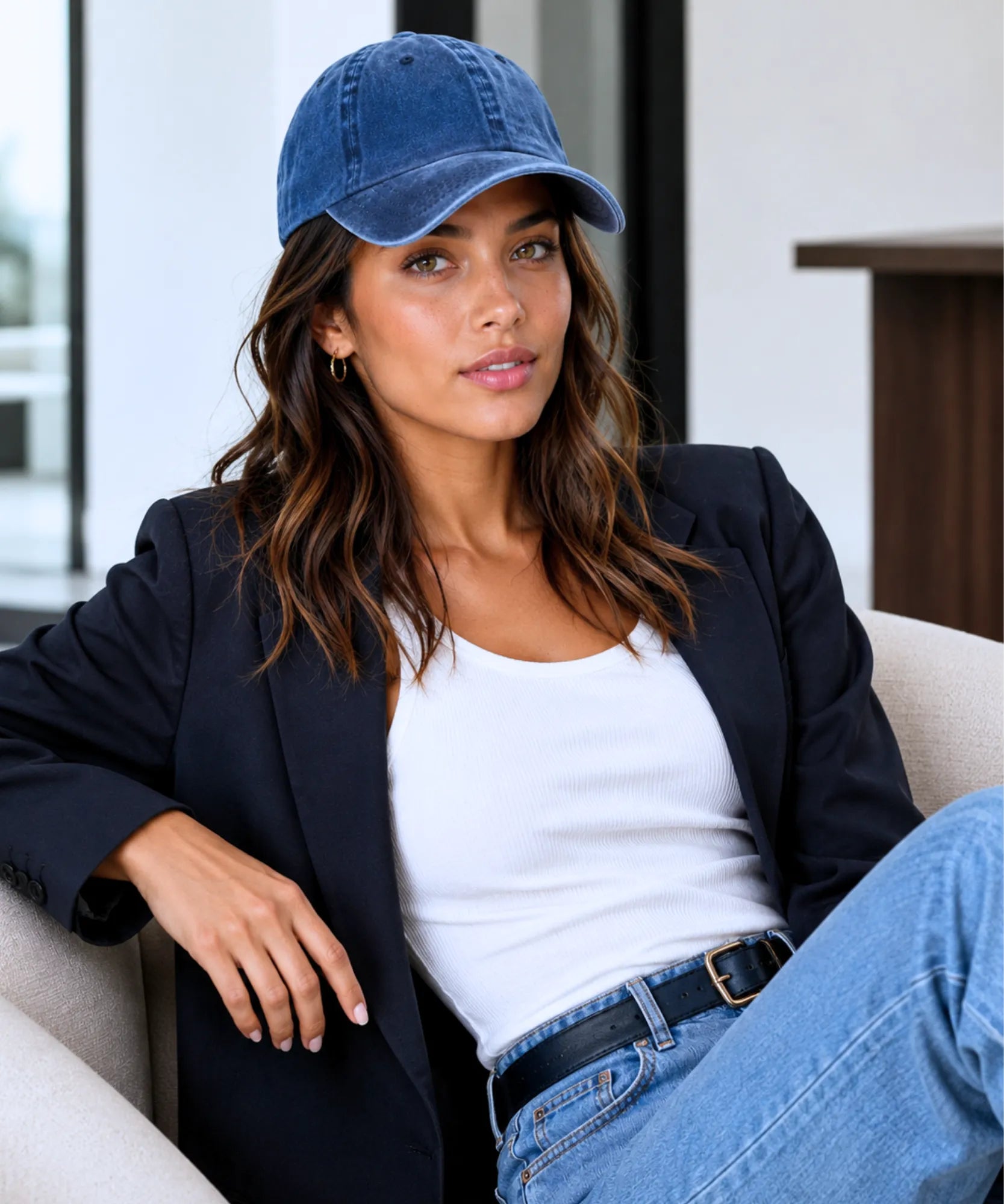 Look completo com boné feminino azul marinho, blazer preto, camiseta branca e jeans