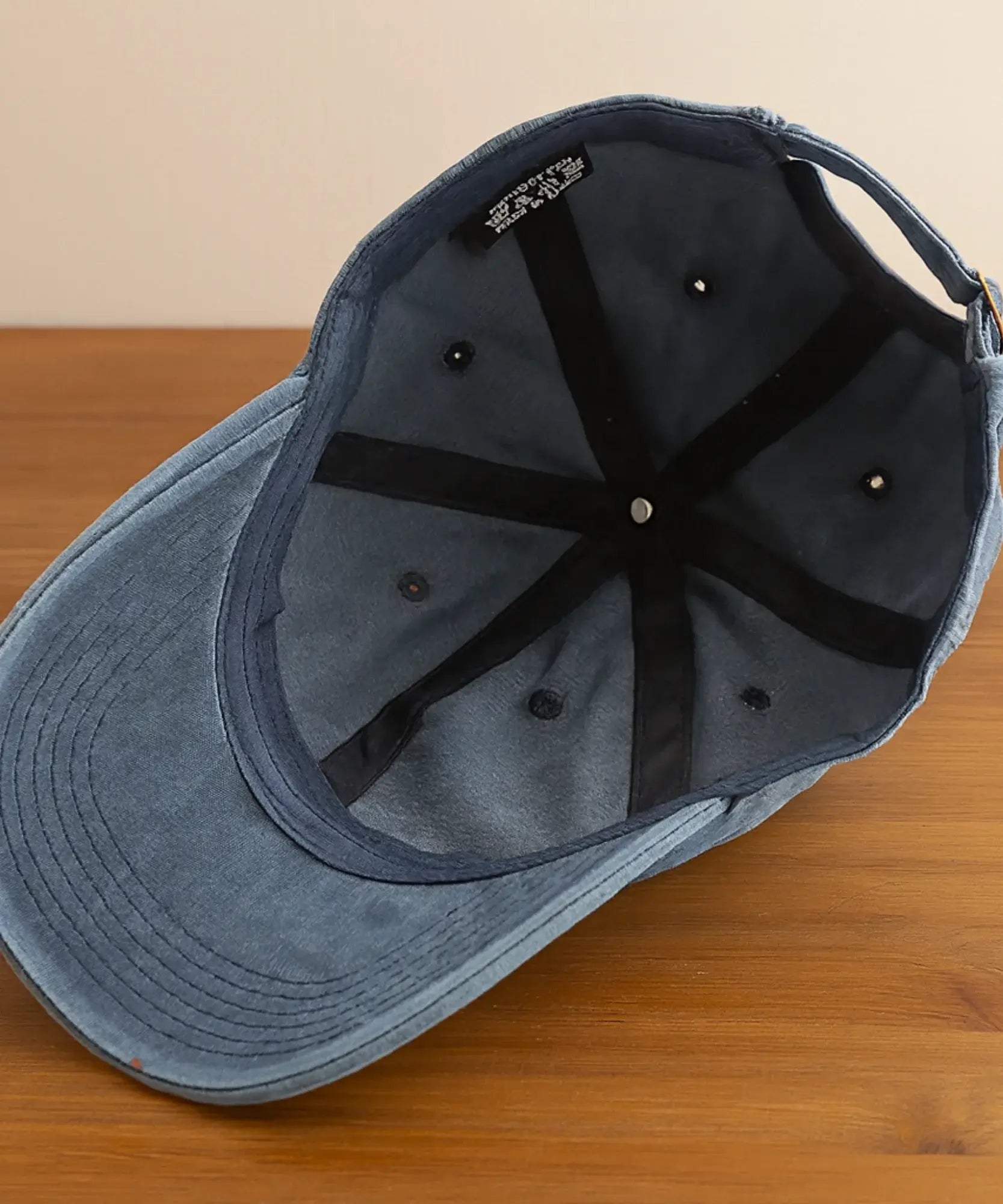 Detalhe interno do boné feminino azul marinho: seis painéis, fita preta nas costuras, ilhós metálicos e fivela de ajuste