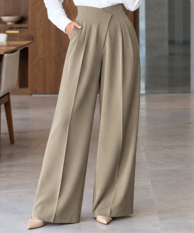 Calça alfaiataria bege feminina wide leg vista de frente, mostrando as pregas fundas e o caimento largo até a barra