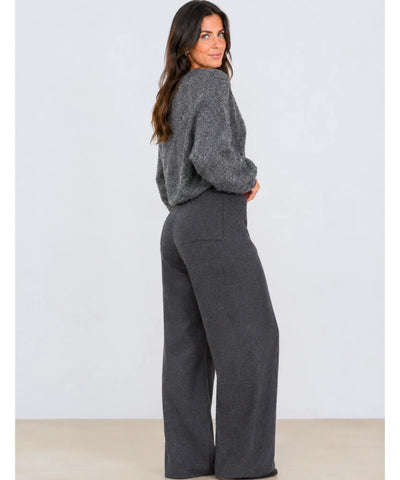 Calça alfaiataria cinza de lã wide leg feminina de perfil em fundo neutro, com tricô cinza por cima