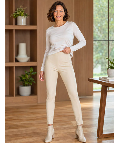 Calça de couro feminina bege slim com blusa clara de manga longa e bota no mesmo tom