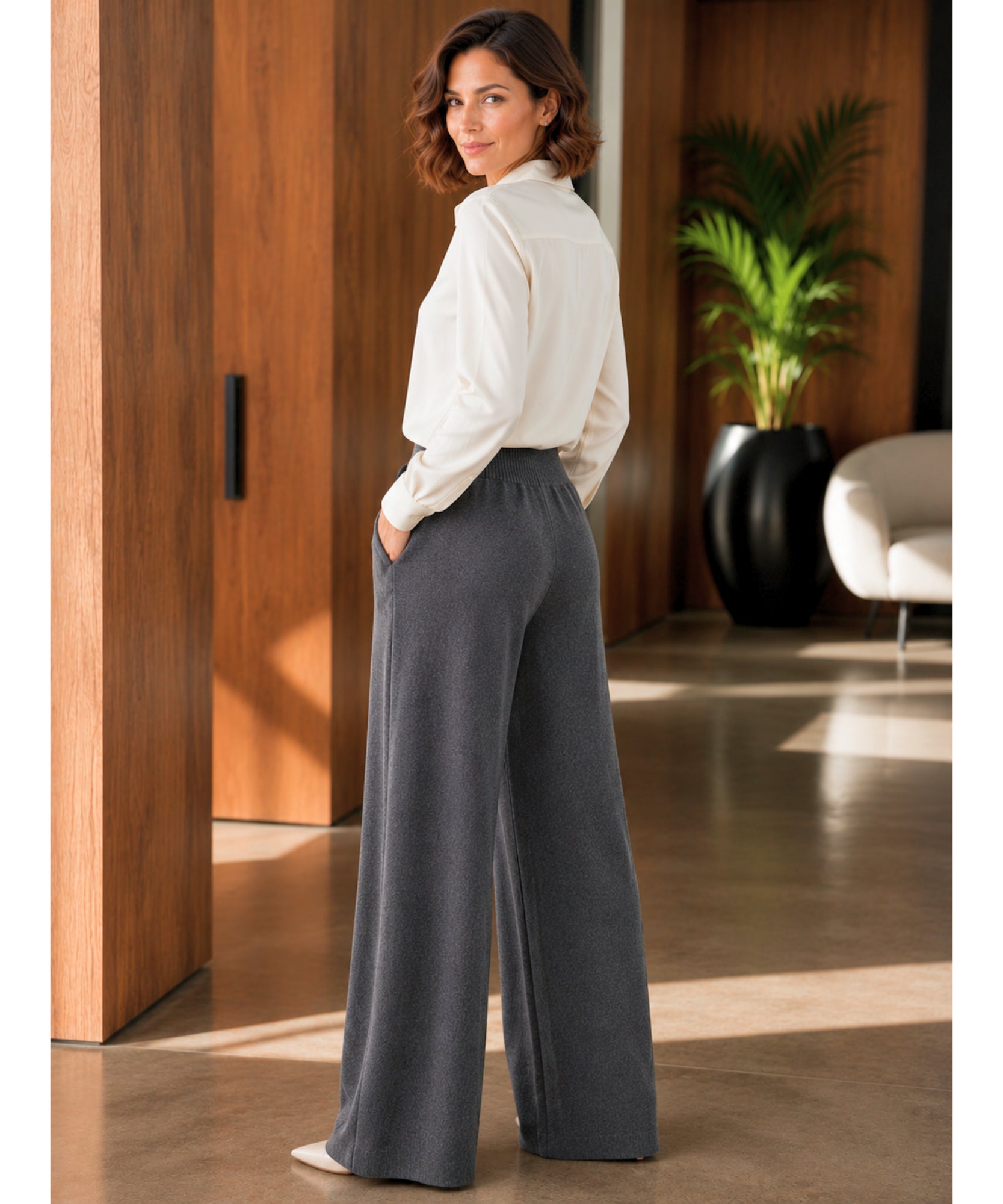 Calça de malha feminina wide leg cinza escuro vista de costas em corpo inteiro, com camisa off white | Anellimn