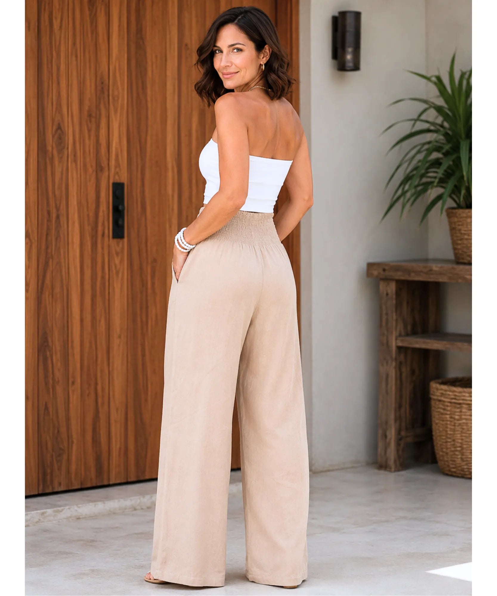 Calça pantalona feminina fluida bege vista de costas, com cós franzido dando a volta completa e costas lisas sem bolso