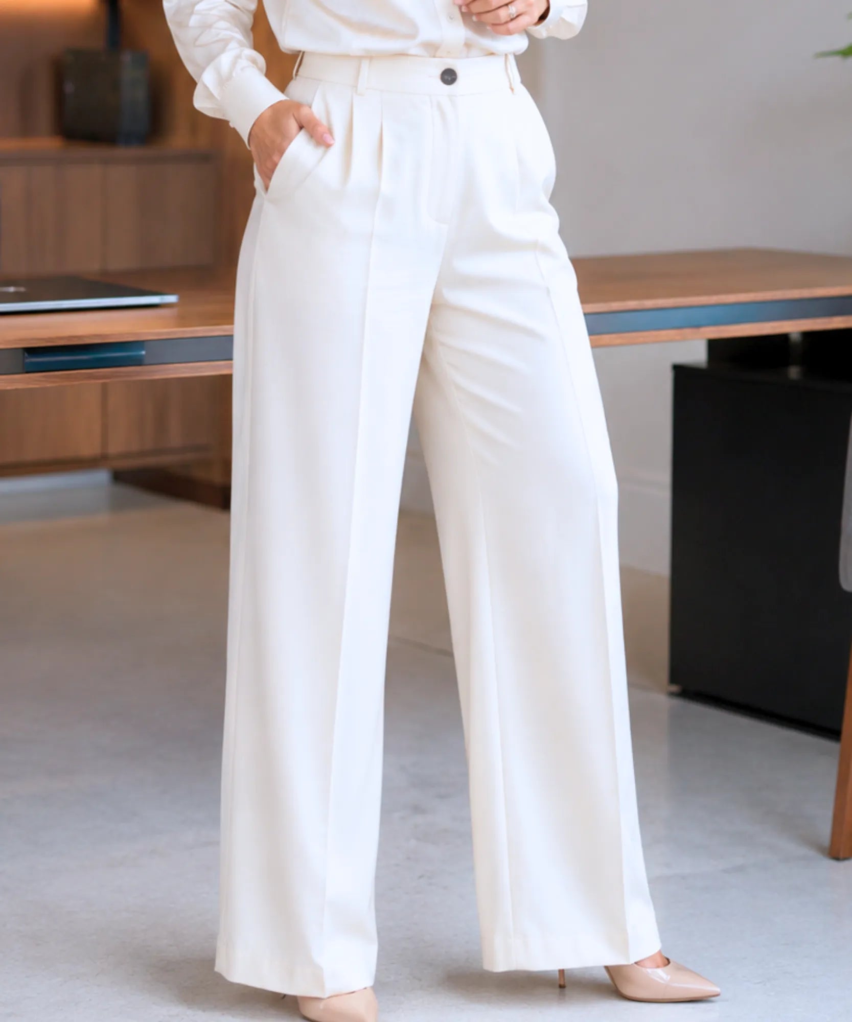 Detalhe do cós alto, das duas pregas frontais, dos passantes e do bolso lateral da calça de alfaiataria off white