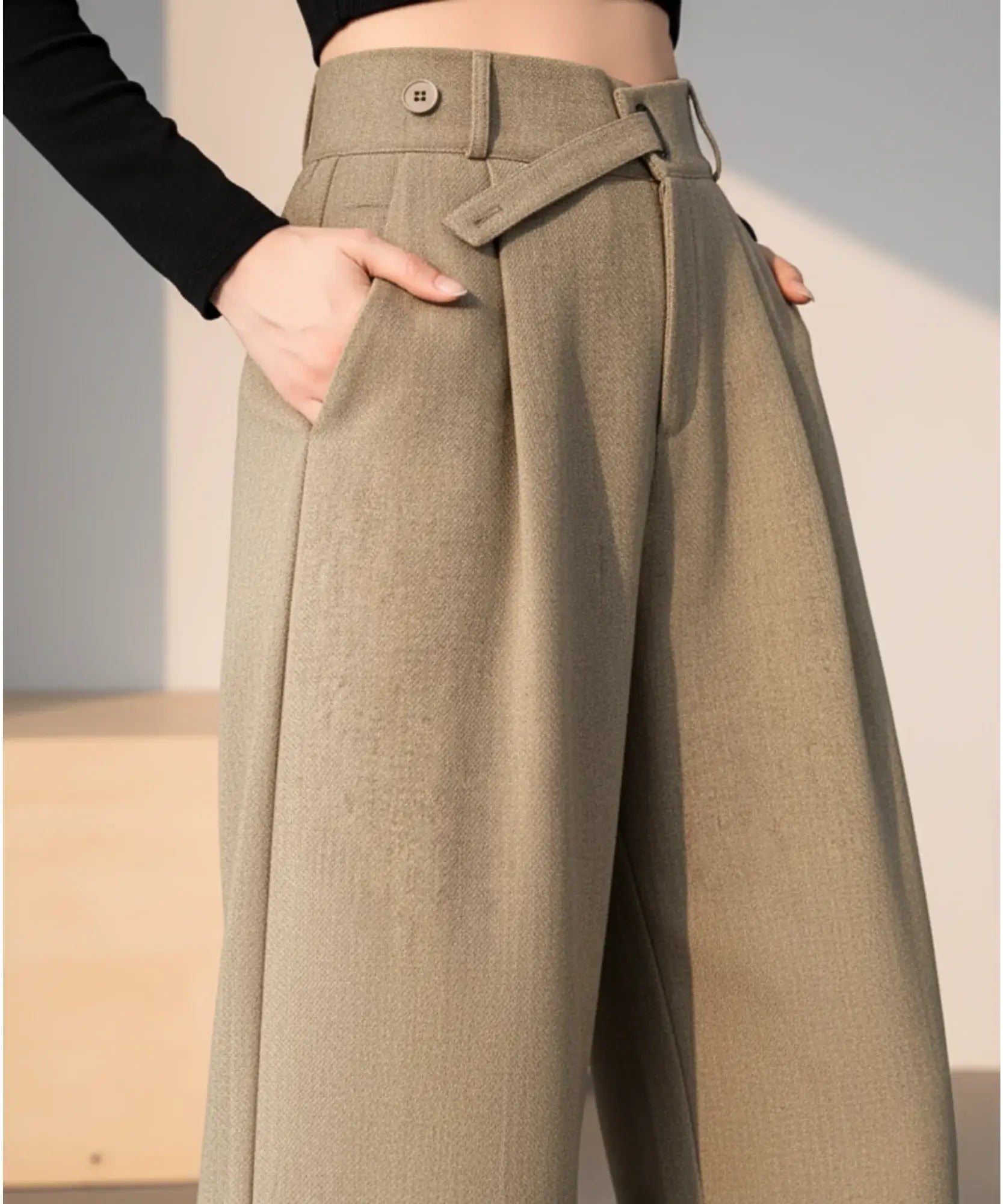 Detalhe da calça wide leg alfaiataria caqui: passador, botão, cinto de tecido e bolso lateral embutido
