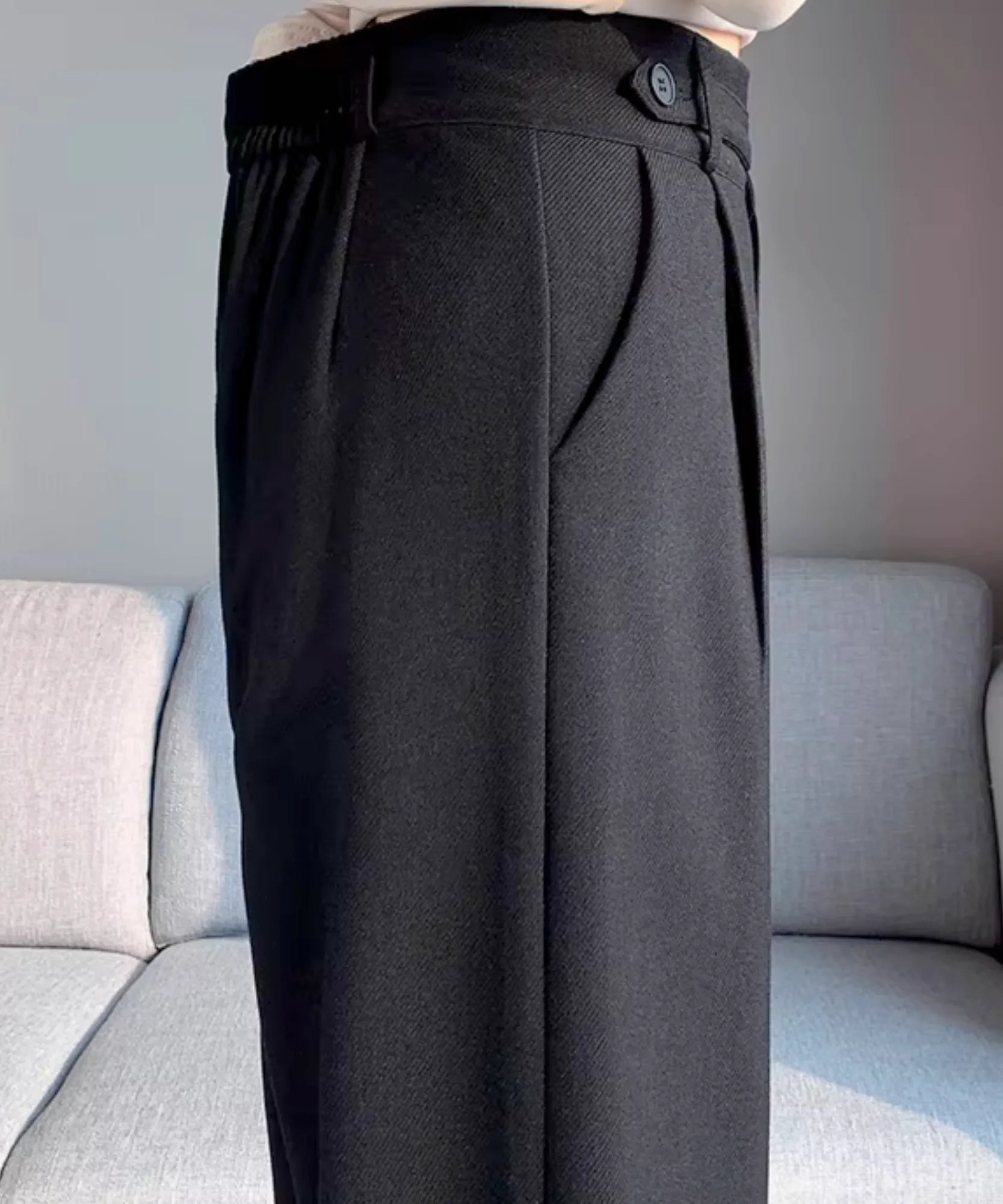 Detalhe do cós traseiro com elástico e botão lateral da calça wide leg alfaiataria preta