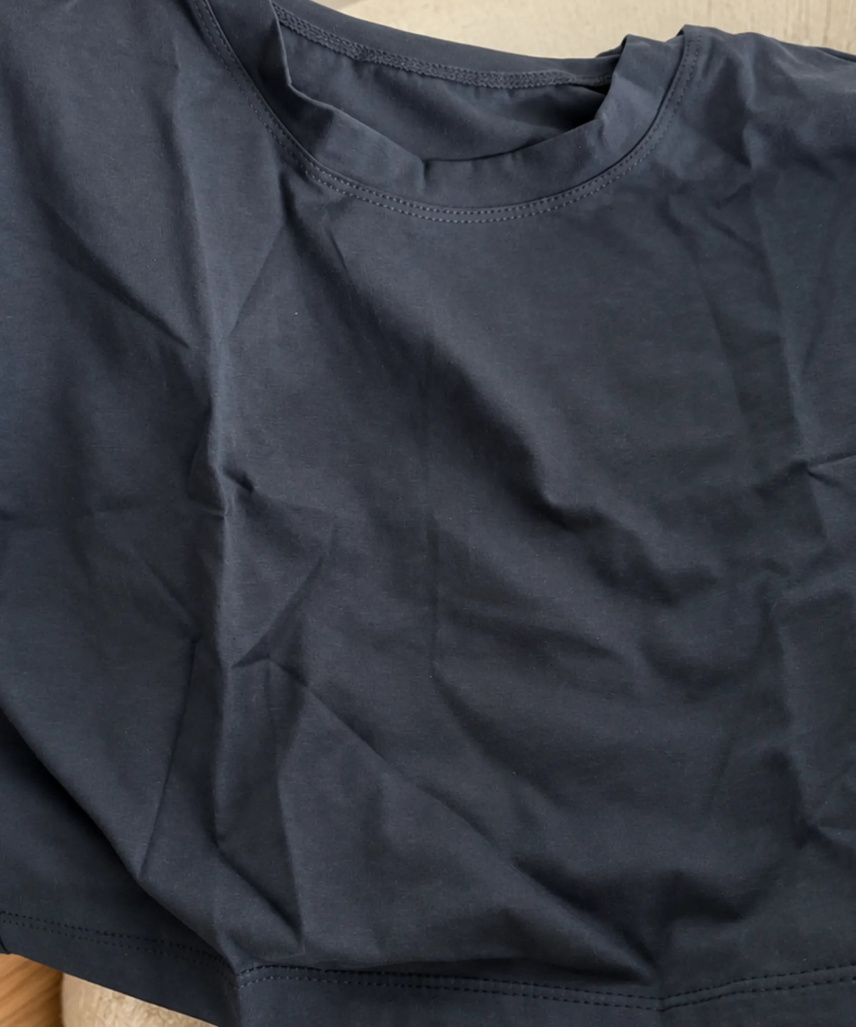Detalhe da malha lisa, da gola redonda com ribana e da costura reforçada do ombro da camiseta cropped oversized feminina