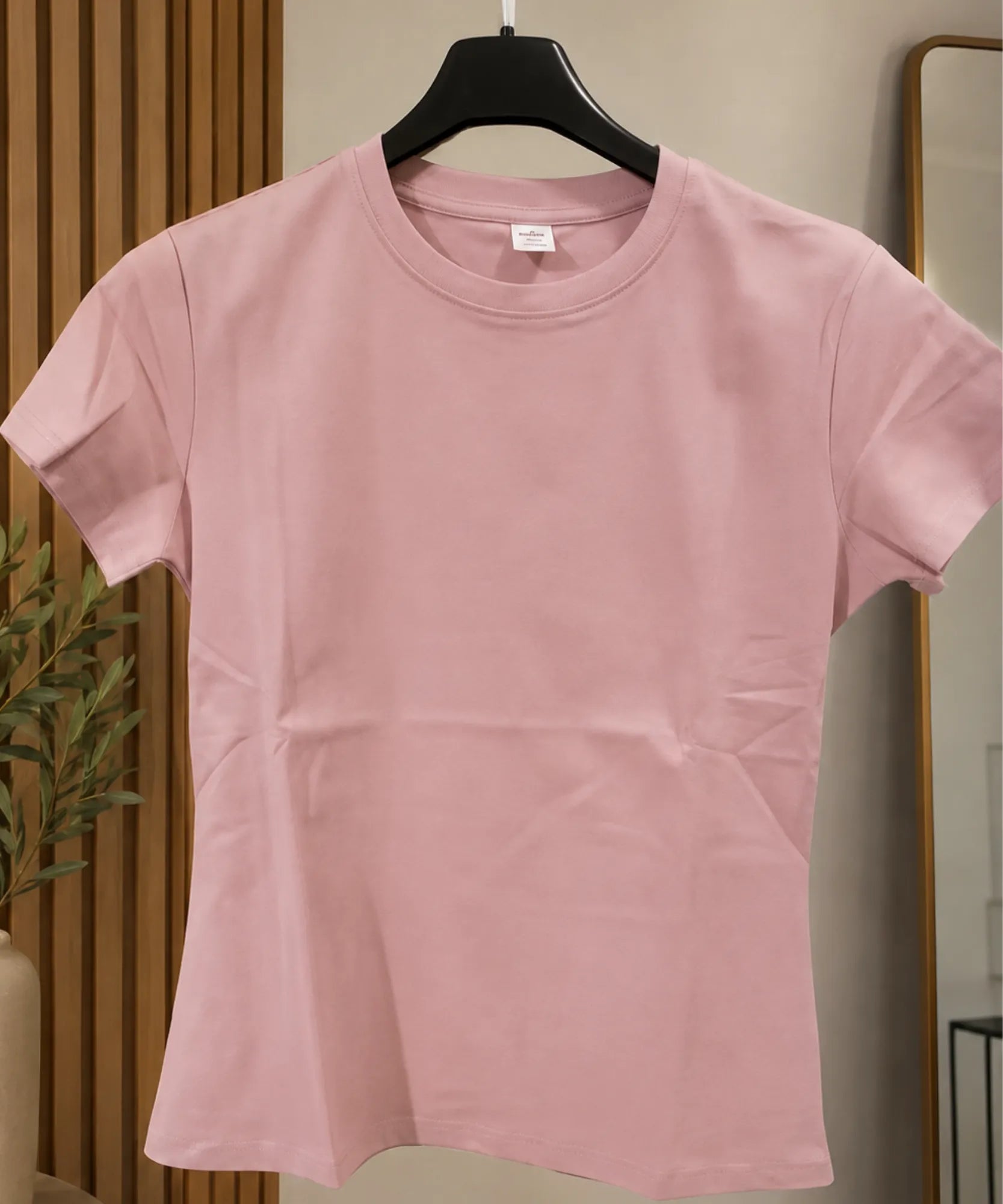 Still da camiseta feminina manga curta rosa claro, pendurada no cabide, detalhe do caimento