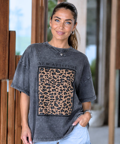 Camiseta oversized feminina preta estonada estampa New Attitude, foto ambientada em varanda de madeira