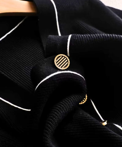 Close do botão dourado e do acabamento em vivo branco do cardigan tricot feminino preto