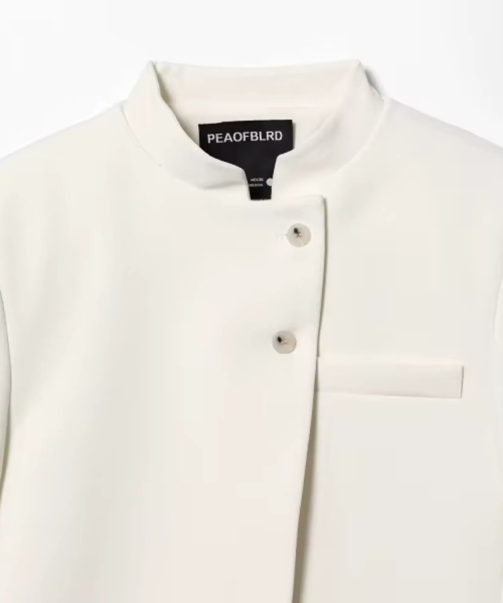 Detalhe da gola padre, dos botões forrados e do bolso chapado do casaqueto off white