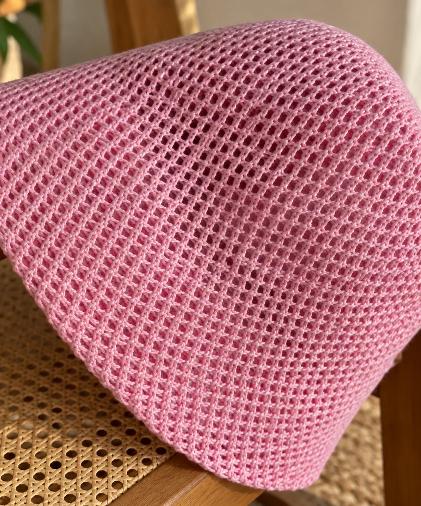 Detalhe da trama vazada do chapéu bucket na cor rosa, malha aberta