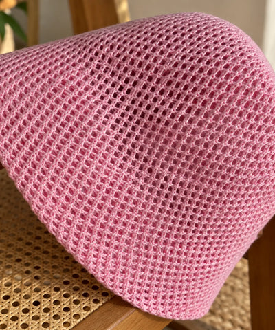 Detalhe da trama vazada do chapéu bucket na cor rosa, malha aberta