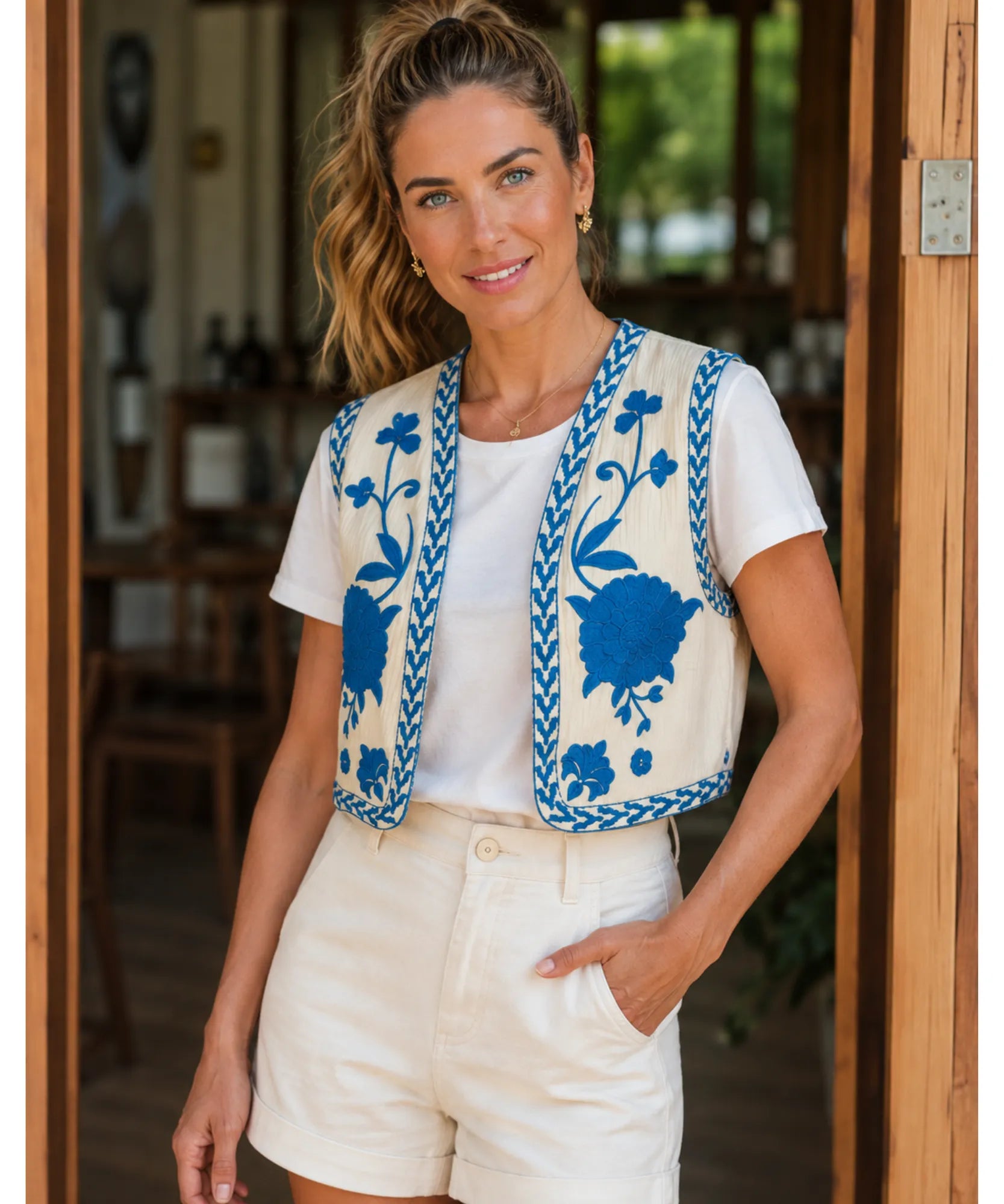 Colete feminino bordado floral bege com bordado azul, modelo vestindo short branco