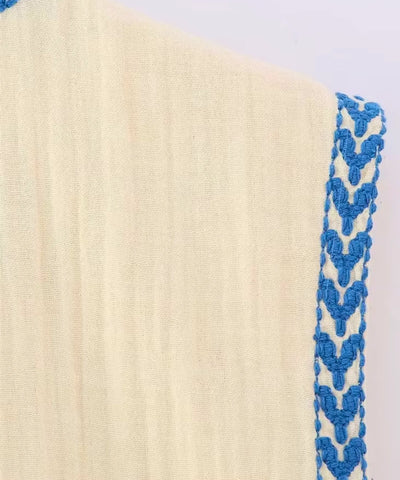 Detalhe do tecido bege com bordado azul do colete feminino boho