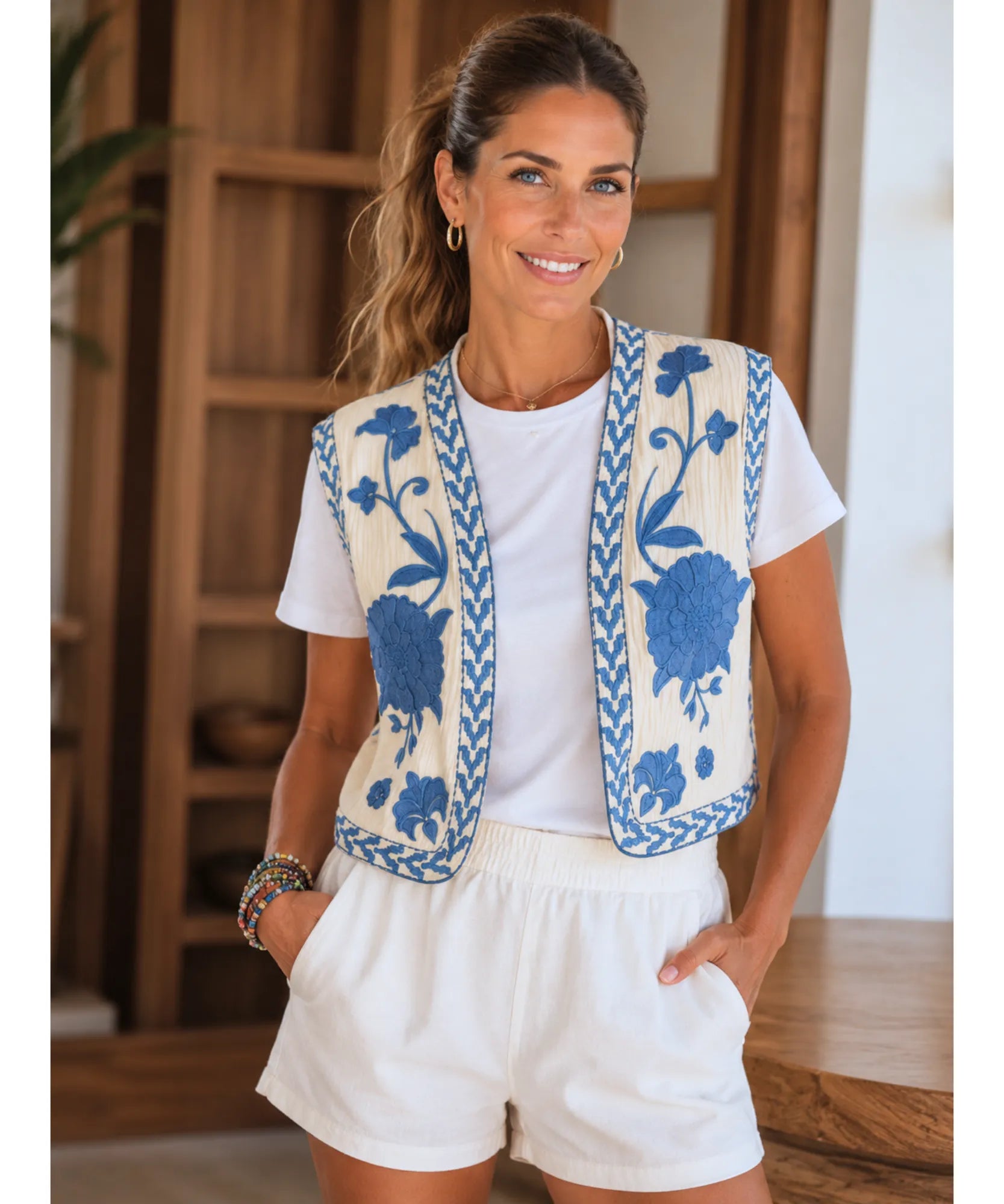 Colete feminino bordado floral bege com bordado azul, modelo vestindo short branco