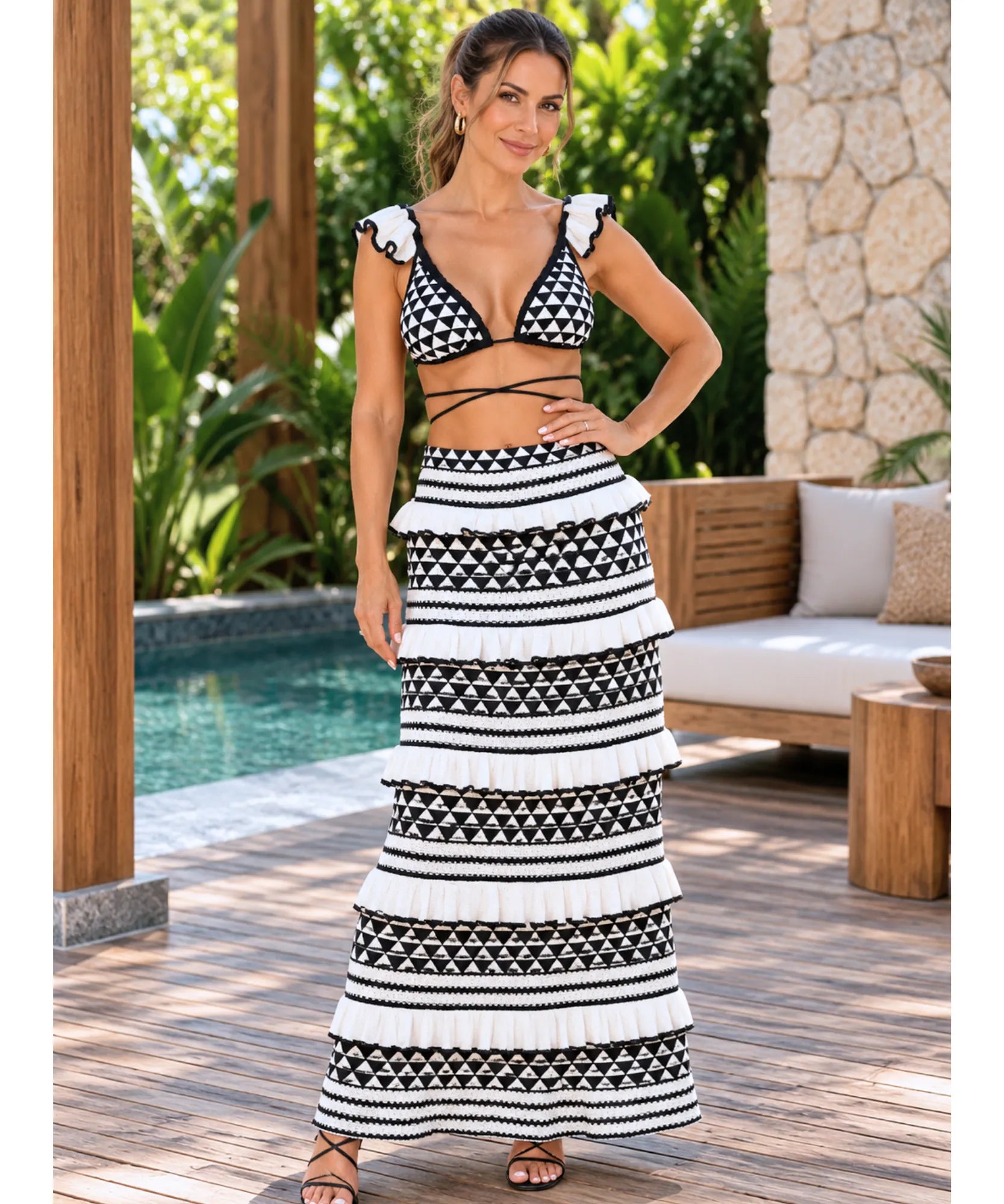 Conjunto biquíni de crochê preto e branco com saia longa à beira da piscina