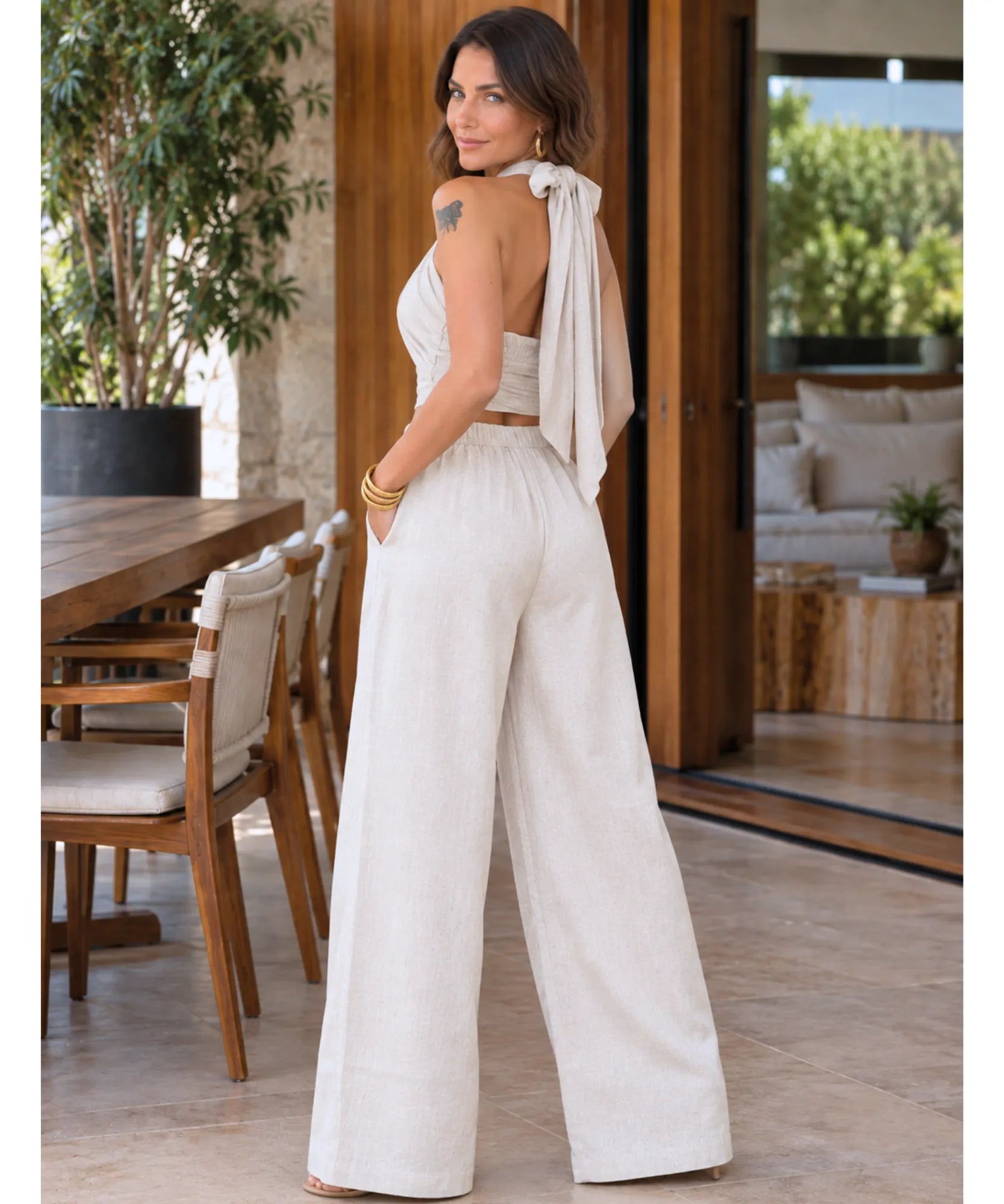 Conjunto cropped e calça pantalona feminino bege, vista de costas corpo inteiro