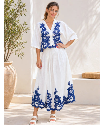 Conjunto branco e azul com blusa bordada e saia plissada midi, vista de frente