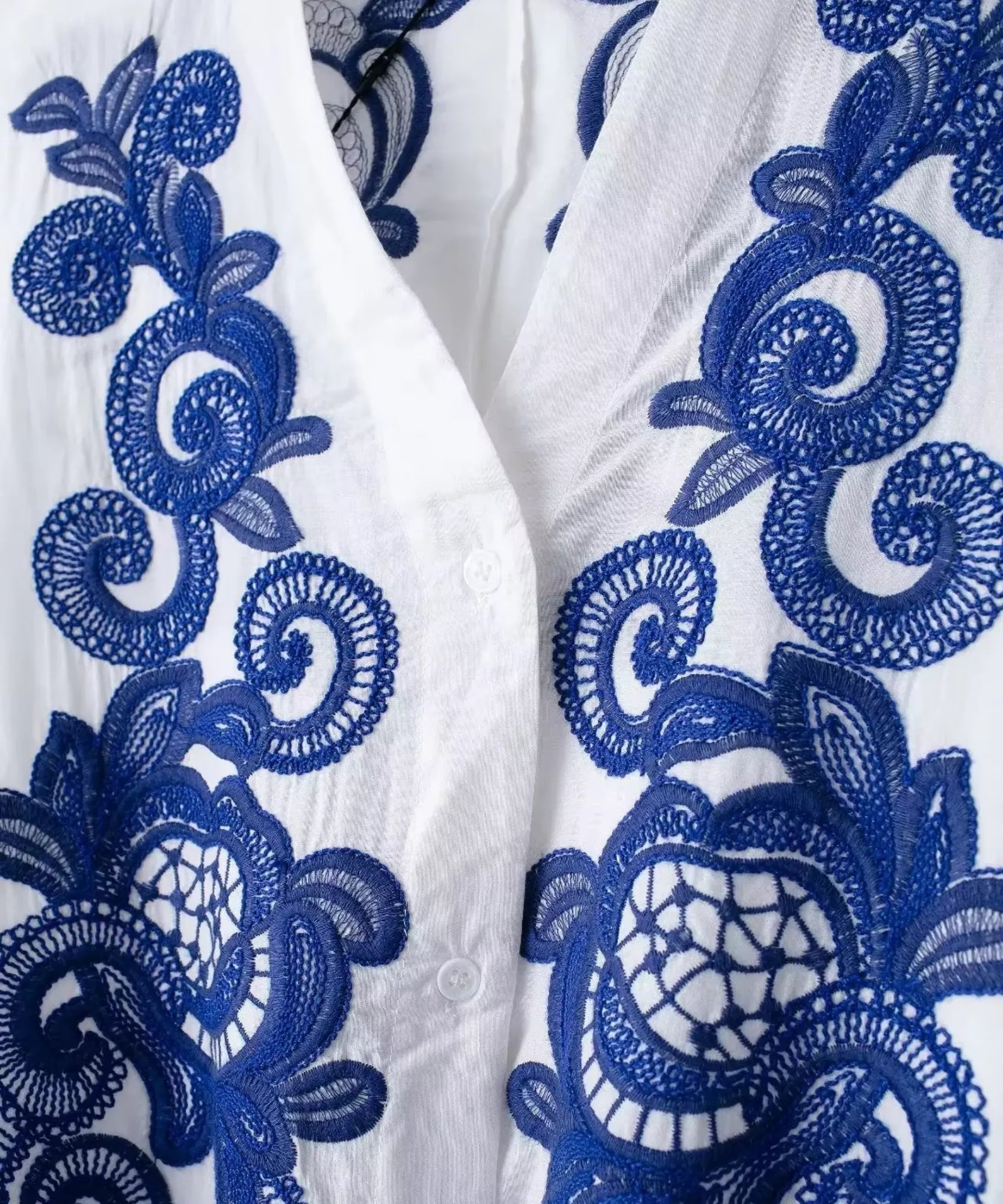 Detalhe do bordado azul no decote em V da blusa branca
