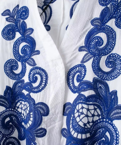 Detalhe do bordado azul no decote em V da blusa branca