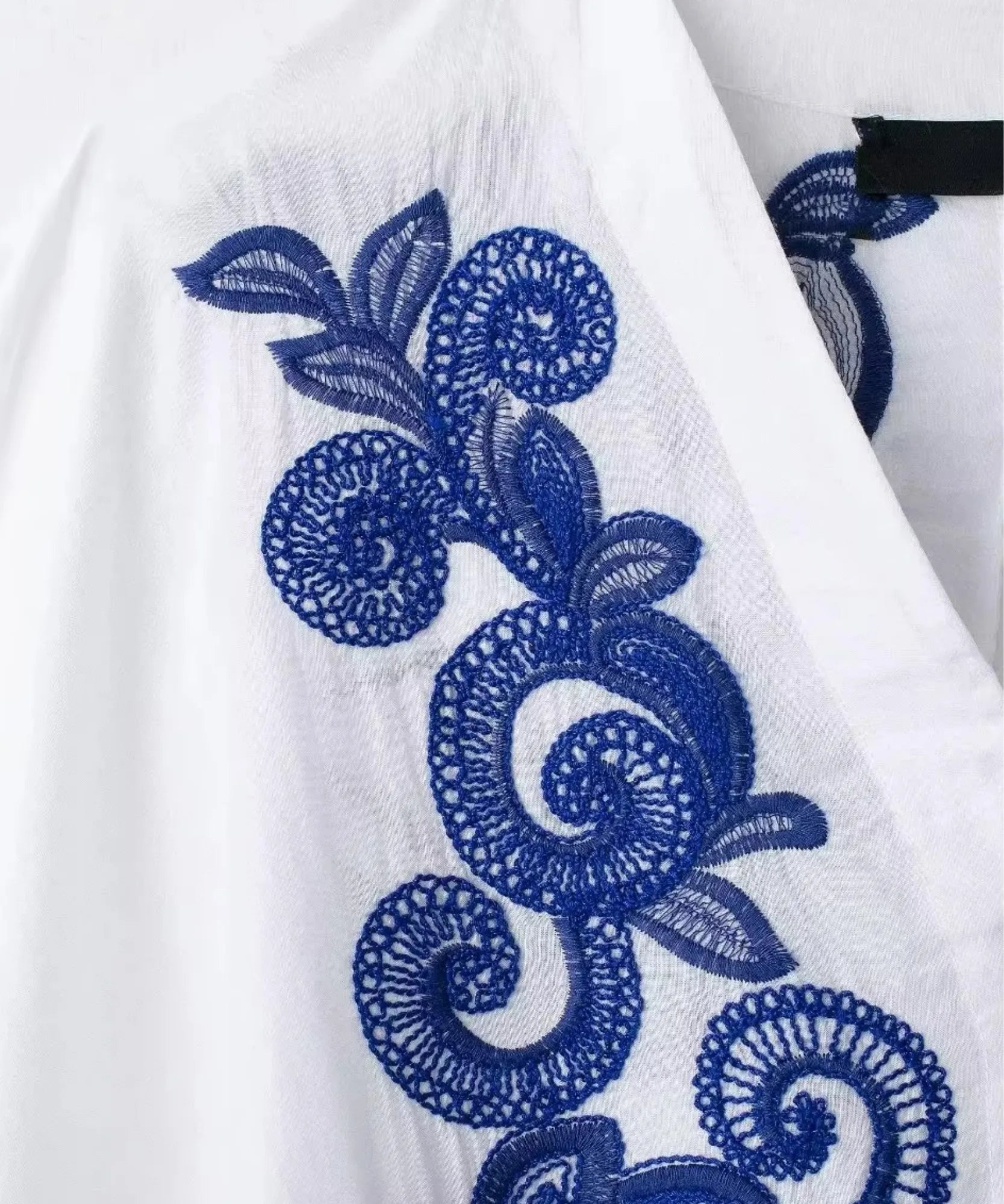 Detalhe do tecido com bordado azul em relevo na manga morcego