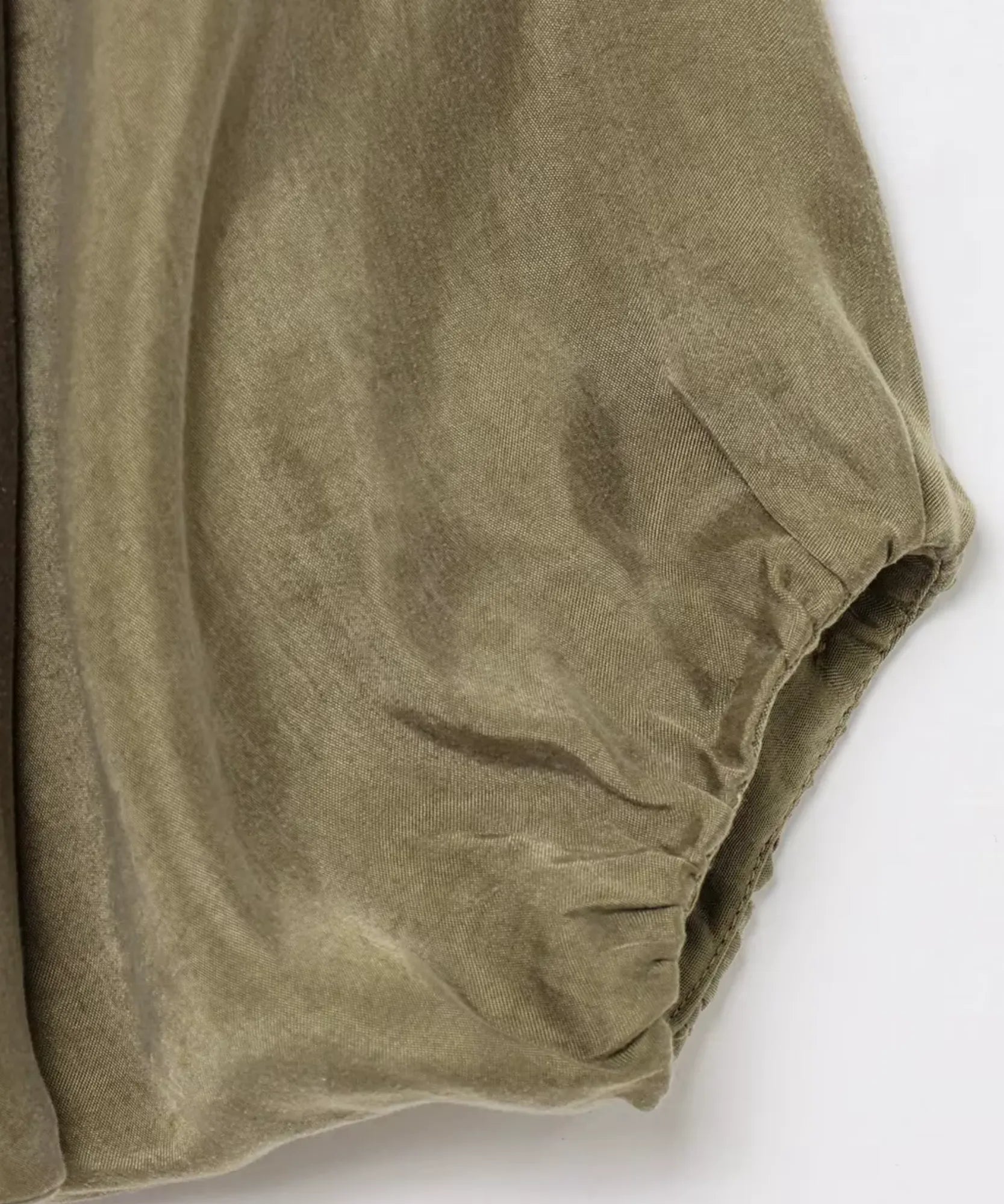 Detalhe da textura acetinada e do punho franzido da jaqueta oversized feminina verde militar